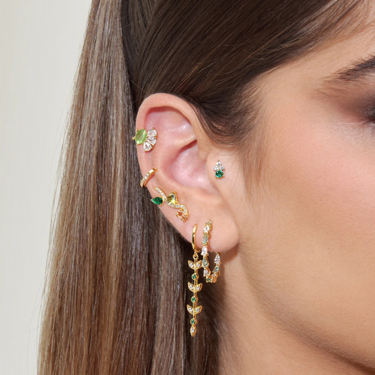mix of gold-plated ear cuffs, hoops, and dangly earrings with green accents and crystal detailing
