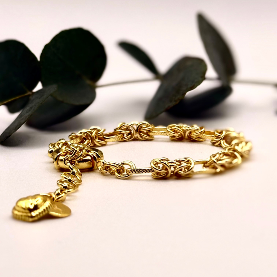 Gridlocked Bracelet — chunky 18k gold-plated chain bracelet with knot-link pattern and heart charm detail.
