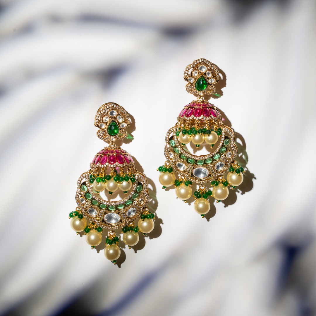 the khaas earrings with gold plated jhumka earrings with red and green stone work and ghungroo pearl drops