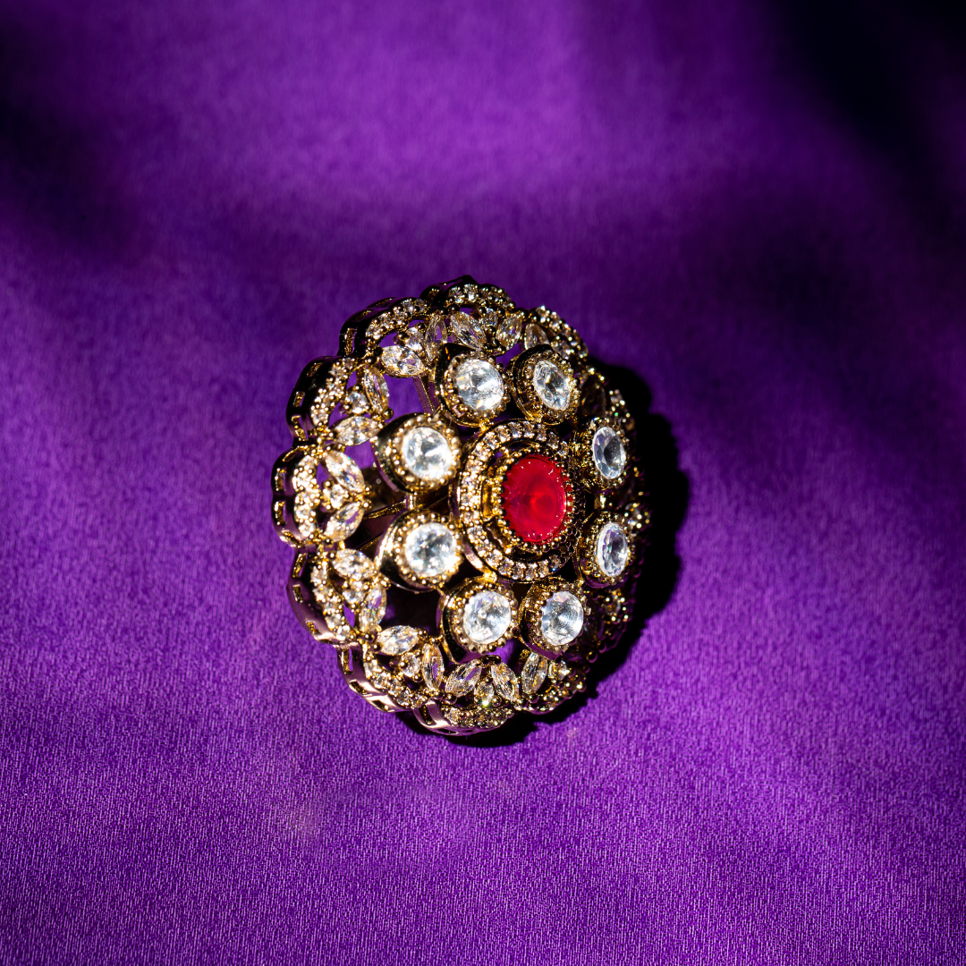 Round gold plated ring with ruby-toned centre stone and crystal detailing.