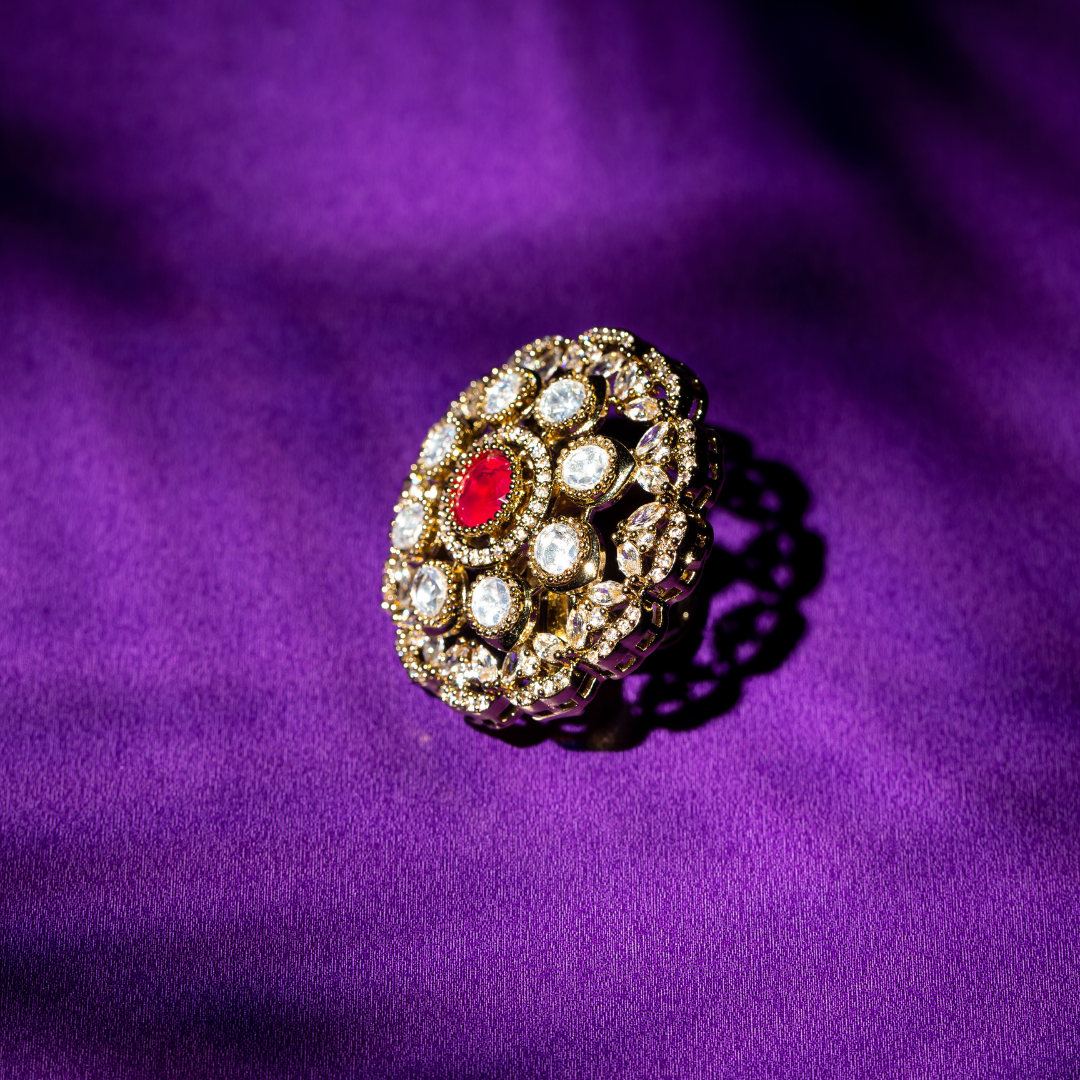 Round gold plated ring with ruby-toned centre stone and crystal detailing.