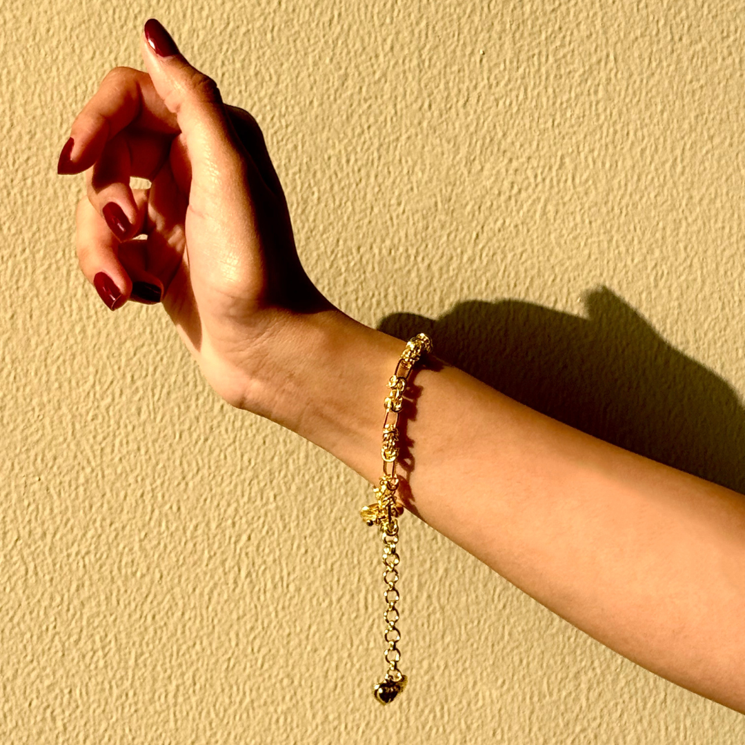 Gridlocked Bracelet — chunky 18k gold-plated chain bracelet with knot-link pattern and heart charm detail.
