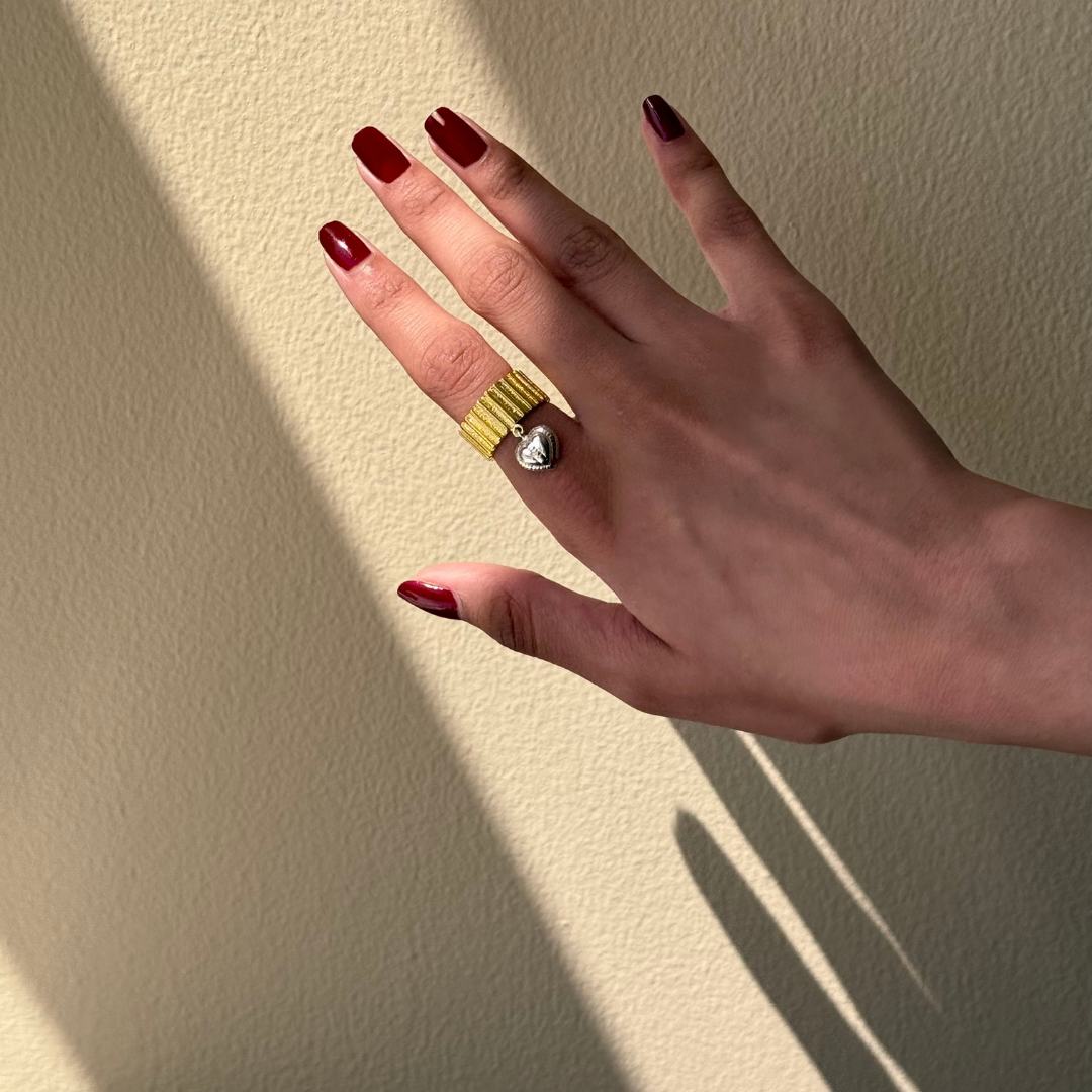 Chunky two-toned gold ring with silver heart charm and ribbed texture
