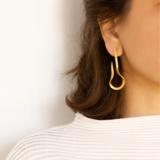 The Curl gold plated brass earring with sculptural fluid shape, contemporary imitation jewelry design