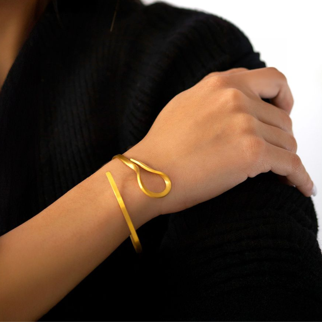 The Curl gold plated brass bracelet with fluid sculptural form, from minimal imitation jewelry collection.