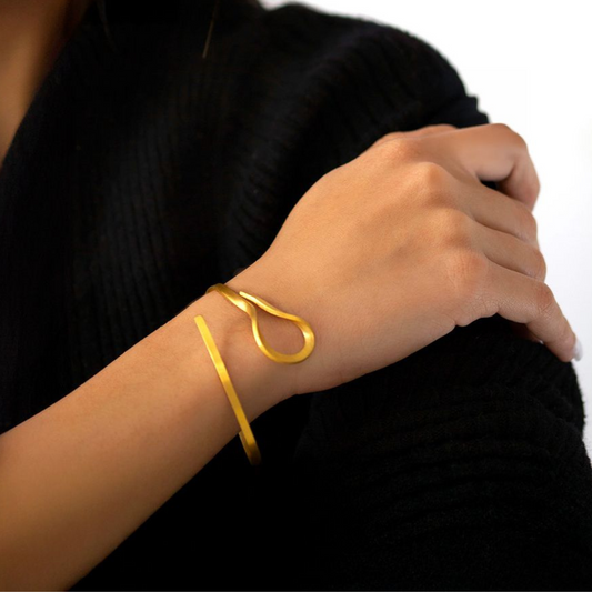 The Curl gold plated brass bracelet with fluid sculptural form, from minimal imitation jewelry collection.