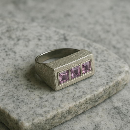 Silver plated ring with three square purple stones in a rectangular setting

