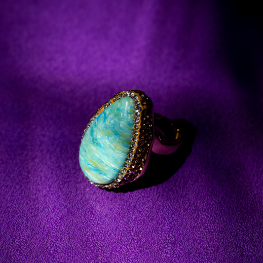 Teardrop ring with cloudy green stone and gold plated setting.







