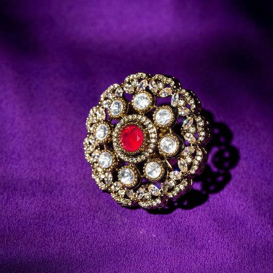 Round gold plated ring with ruby-toned centre stone and crystal detailing.