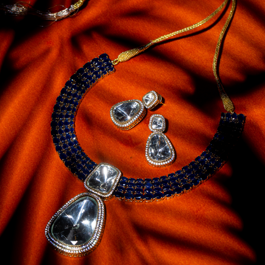 The Reign Necklace Set in gold plated brass with glass polki pendants and sapphire blue crystal accents, includes matching earrings.
