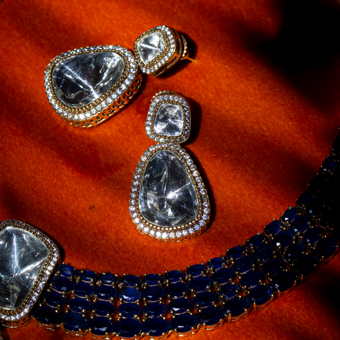 The Reign Necklace Set in gold plated brass with glass polki pendants and sapphire blue crystal accents, includes matching earrings.

